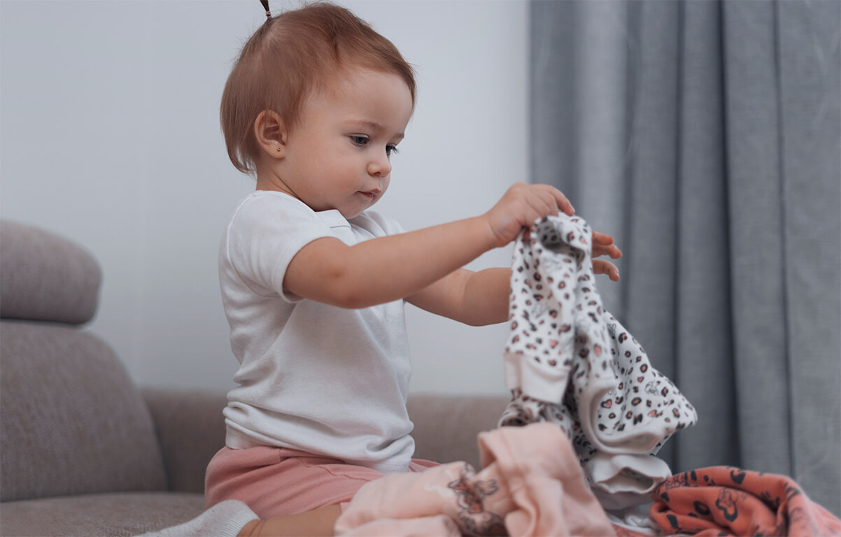 دختر بچه‌ای در حال تا کردن لباس‌های خود 