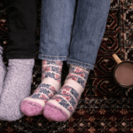 عکس از نمای بالا از زوجی که جوراب پشمی پوشیده اند و دو لیوان در کنارشان است.