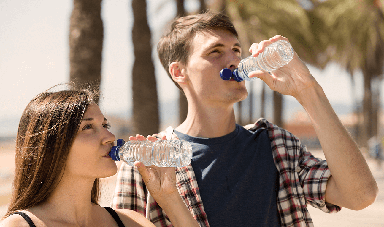زوج جوان در حال نوشیدن آب در فضای باز 